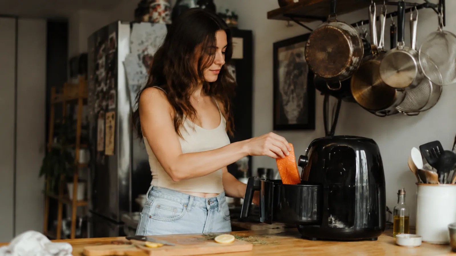 Person placing salmon fillet into Cosori air fryer basket in a small apartment kitchen