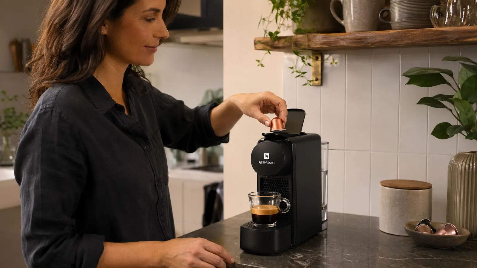 Hand inserting a Nespresso Original Line capsule into the Essenza Mini pod slot