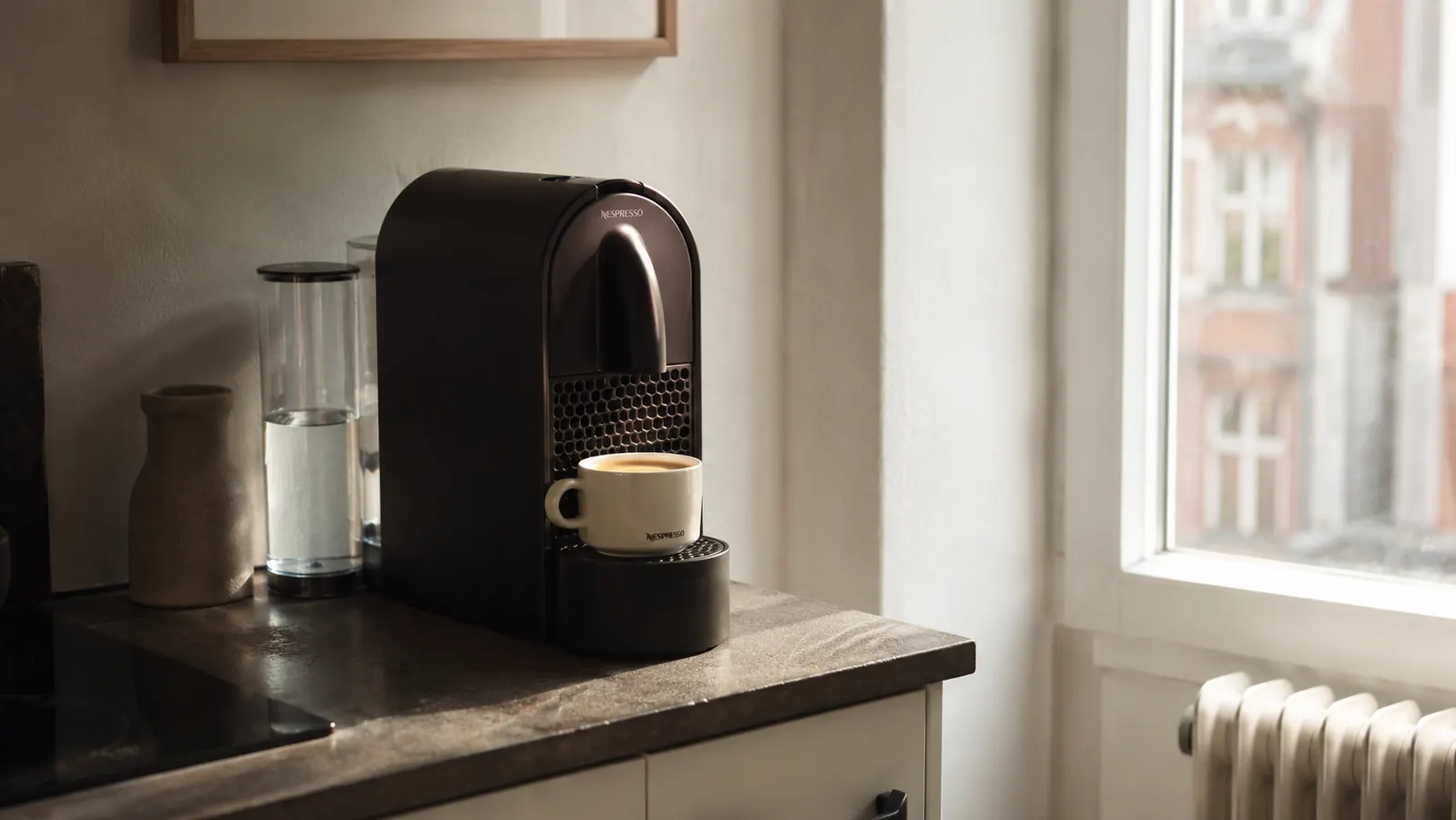 Nespresso Essenza Mini espresso machine on a small apartment kitchen counter next to a single espresso cup